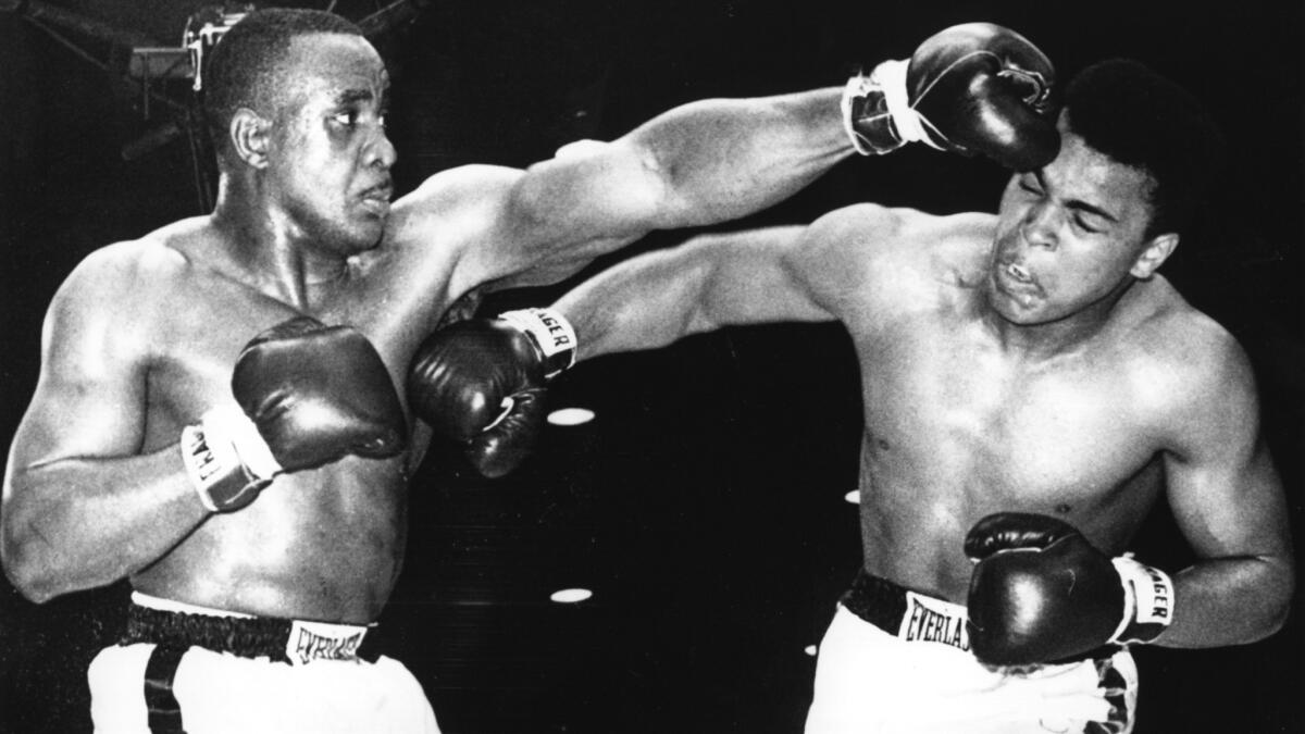 Heavyweight champion Sonny Liston, left, and Muhammad Ali exchange punches during their first fight in Miami on Feb. 25, 1964. Ali, then known as Cassius Clay, defeated Liston by technical knockout in the seventh round to claim the title.