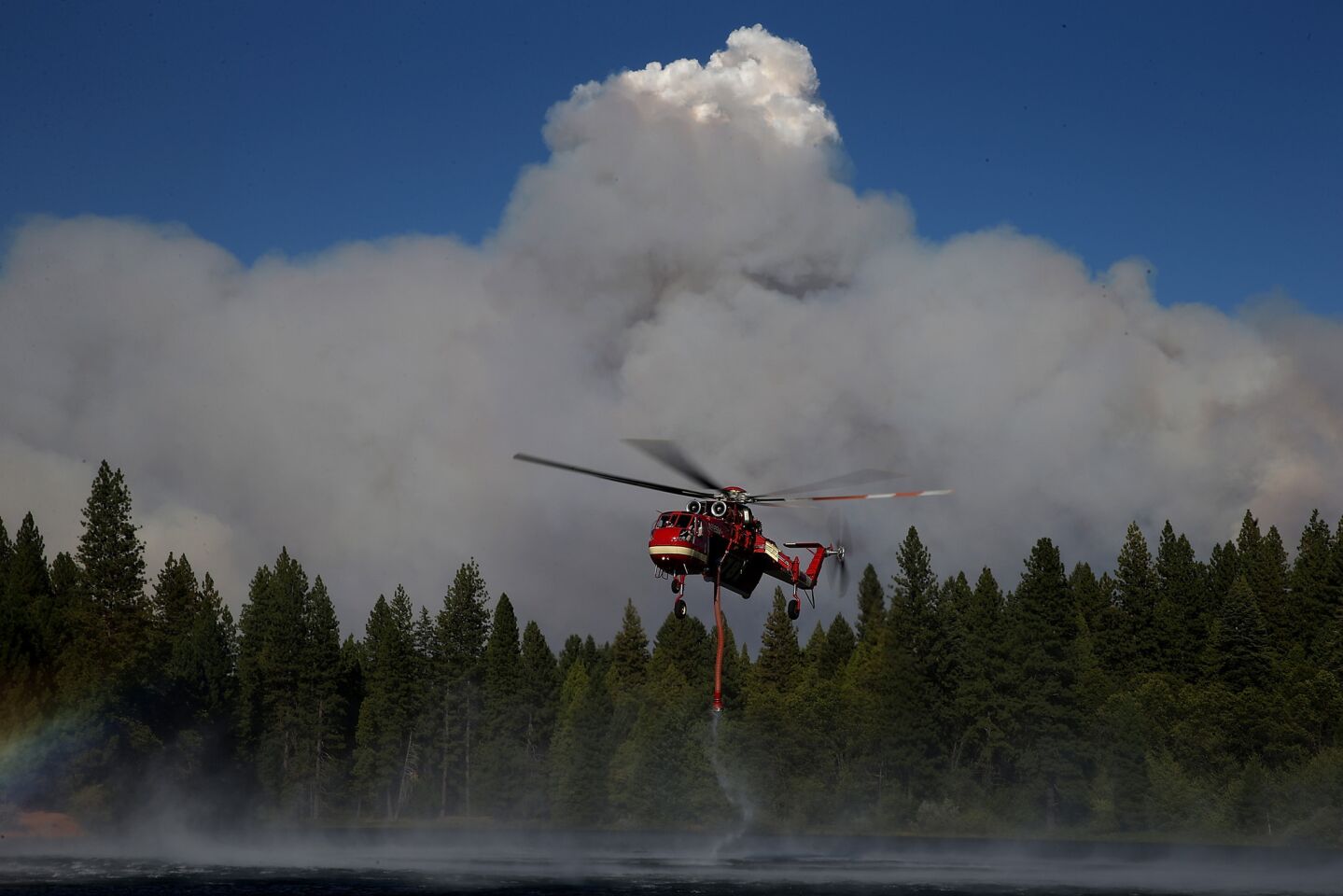 A firefighting helicopter collects water from a reservoir to fight the King fire in Pollock Pines, Calif.