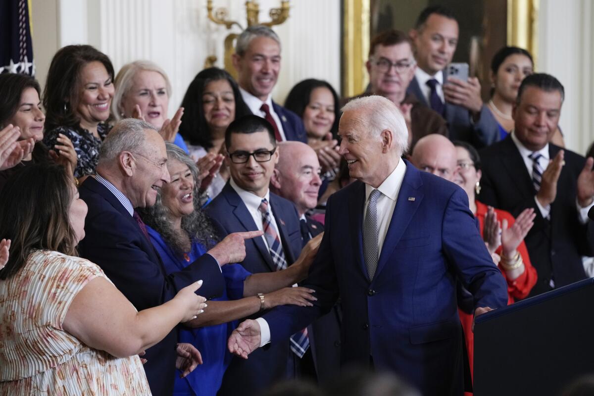 El presidente Joe Biden saluda a personas en el estrado después de su discurso 
