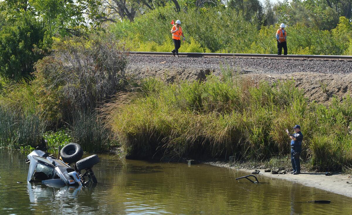 An investigator takes pictures of a mangled truck as it lies in the water after colliding with a train in Northern California on Thursday. Authorities say a woman floating on a Delta canal was seriously hurt when an Amtrak train struck the pickup and knocked it into the water.