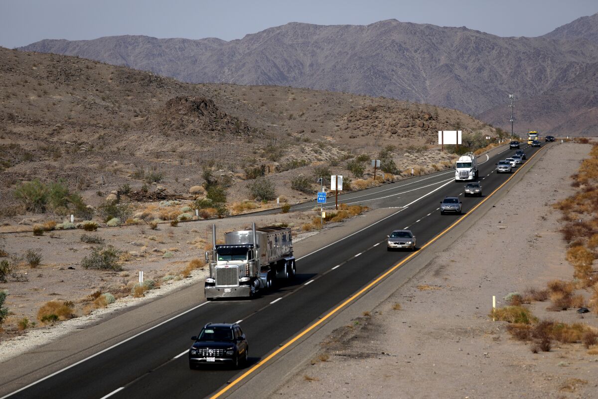 Cars and trucks on a two-lane freeway through desert mountains