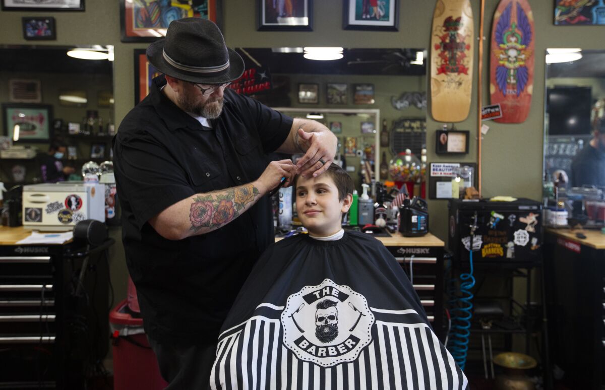 Pedro Delafuente, co-owner of Old Town Barber in Temecula, gives 14-year-old Chris Kavanaugh Jr. a haircut Tuesday.