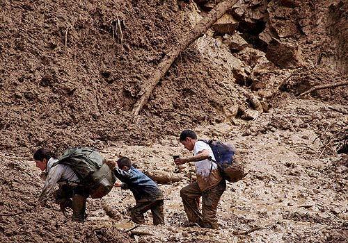 A group of bus passengers try to cross an area affected by an early-morning landslide that swept away several vehicles in central Colombia. Eight people were injured.