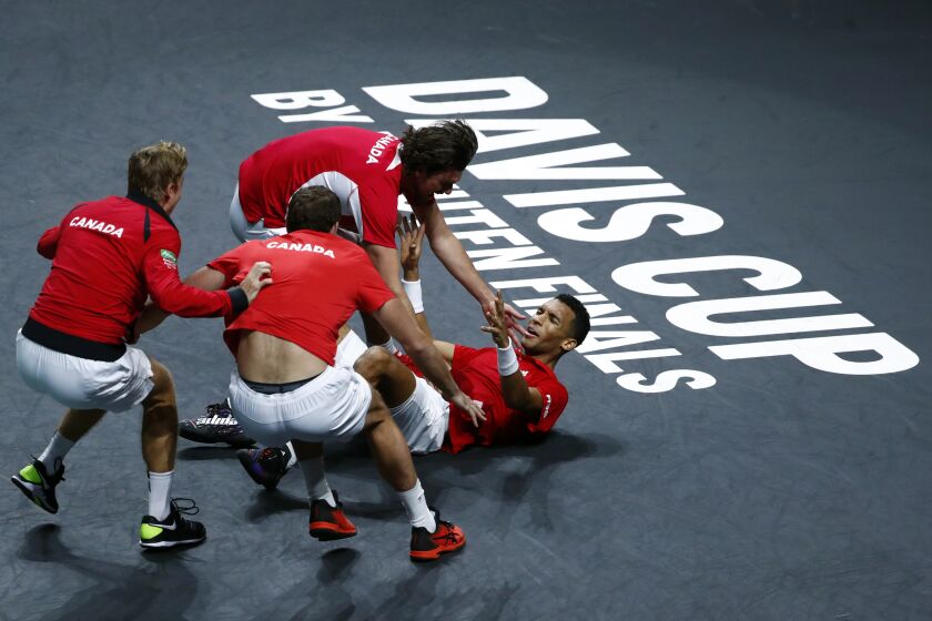 Canada's Felix Auger Aliassime, right, celebrates with teammate after defeating Australia's Alex de Minaur during the final Davis Cup tennis match between Australia and Canada in Malaga, Spain, Sunday, Nov. 27, 2022. (AP Photo/Joan Monfort)