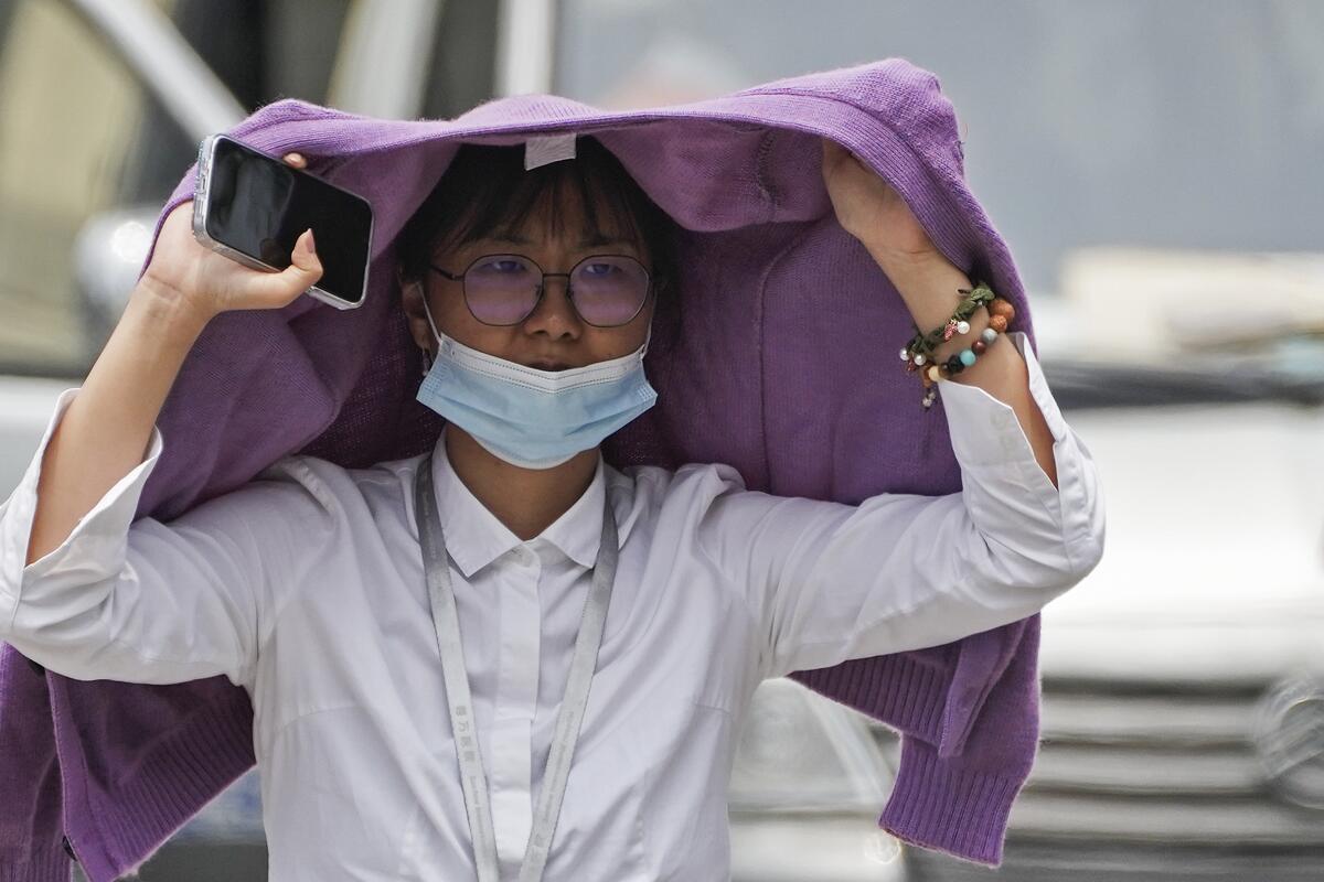 A woman uses a sweater to shield from the sun