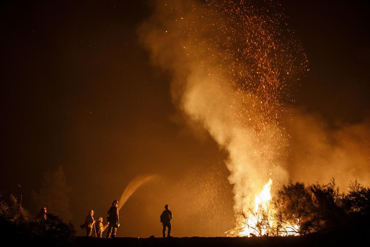 Firefighters on the Mendocino Complex fire monitor a burn operation on top of a ridge near the town of Ladoga, Calif.