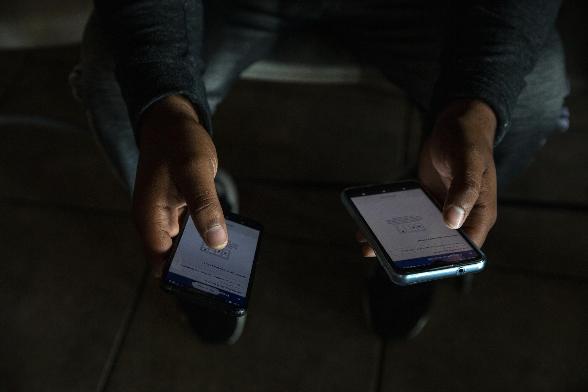 A man uses two phone to try to make an appointment to seek asylum into the United States.