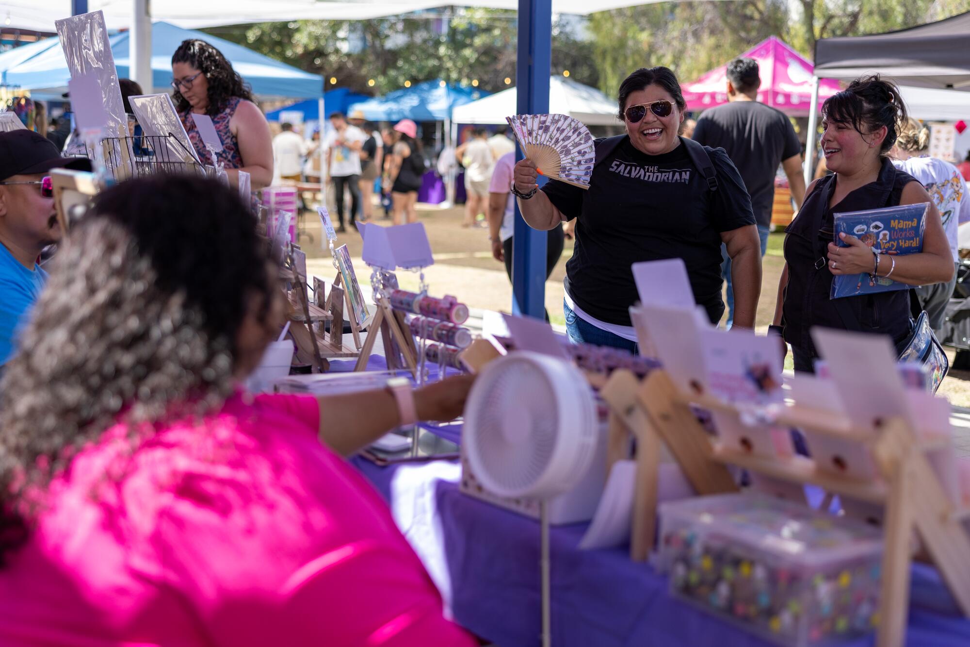 Sandra Lanz, left, and Claudia Maldonado, right, talk to a vendor at Púchica Fest in L.A.