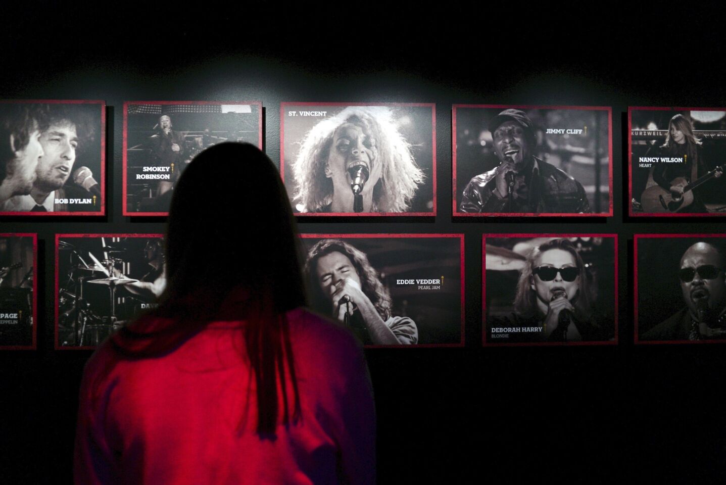 A woman looks at photos of Hall of Fame inductees at the Rock & Roll Hall of Fame in Cleveland.