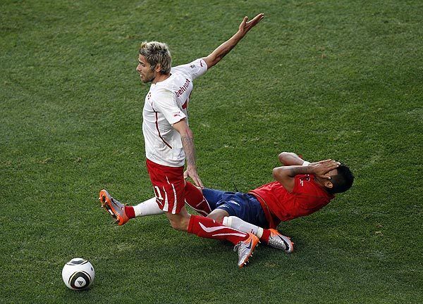 Chile's Arturo Vidal, right, falls on the ground after contact with Switzerland's Valon Behrami during a World Cup Group H match at Nelson Mandela Bay Stadium in Port Elizabeth, South Africa, on Monday. Behrami received a red card moments after the tackle and was ejected.