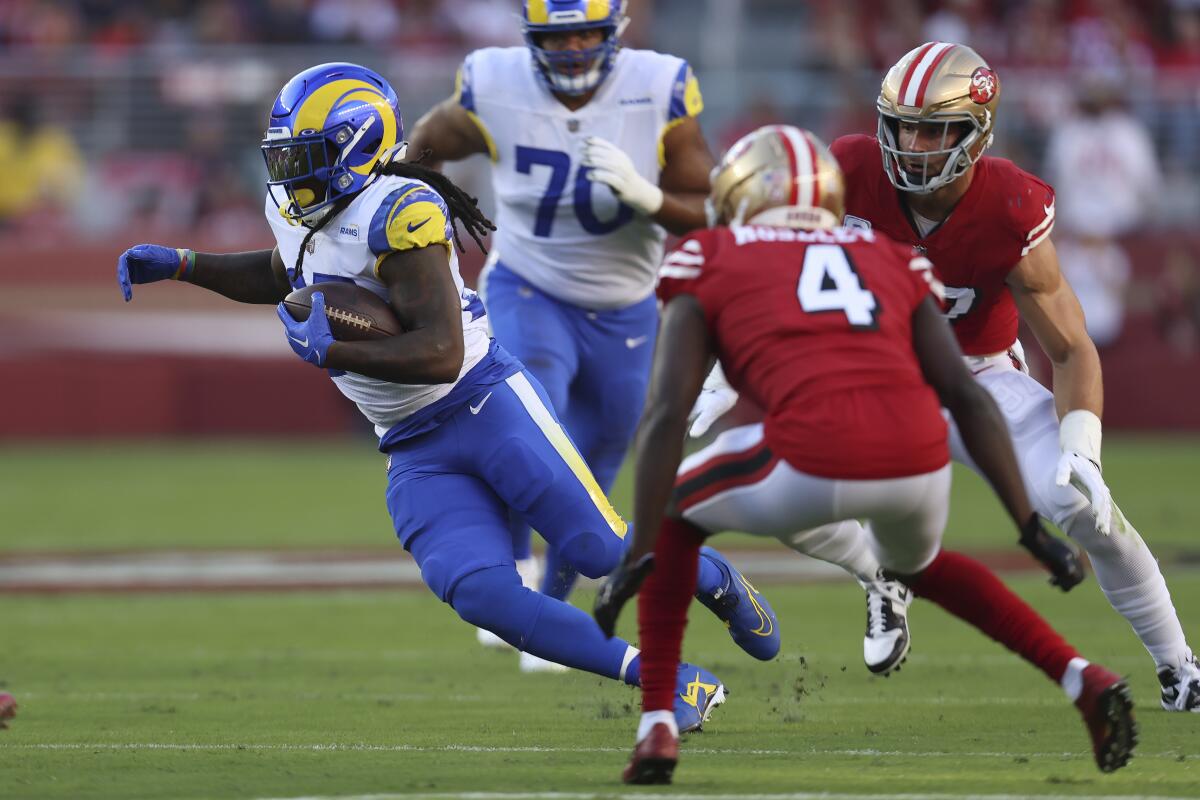 Rams running back Darrell Henderson Jr. cuts away from a 49ers defender.