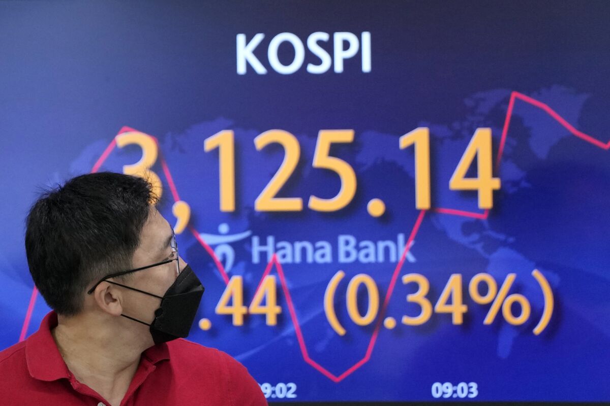 A currency trader walks by the screen showing the Korea Composite Stock Price Index (KOSPI) at the foreign exchange dealing room in Seoul, South Korea, Friday, Sept. 10, 2021. Shares were higher in Asia on Friday as investors stepped up buying despite another decline on Wall Street that kept the S&P 500 and the Nasdaq on track for their first weekly losses in three weeks.(AP Photo/Lee Jin-man)