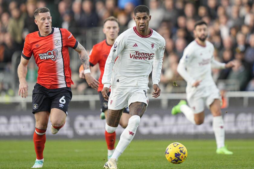 Manchester United's Marcus Rashford runs with the ball chased by Luton Town's Ross Barkley.