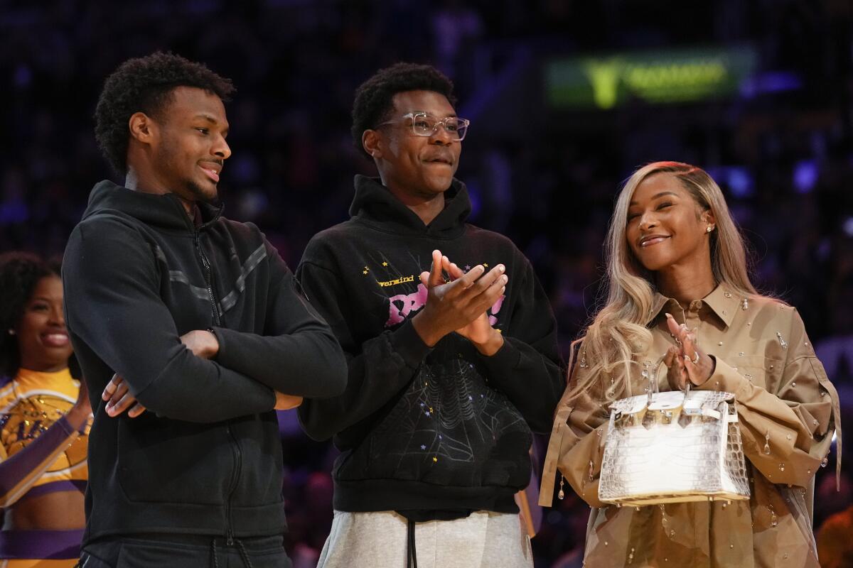 Bronny, left, and Bryce James and their mother, Savannah, applaud during a ceremony honoring LeBron James.