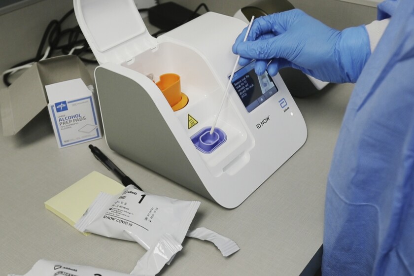 A lab technician works with an Abbott Laboratories test machine. Federal health officials are warning about potential accuracy problems with the rapid test for COVID-19 used at thousands of hospitals, clinics and testing sites across the U.S., including the White House.