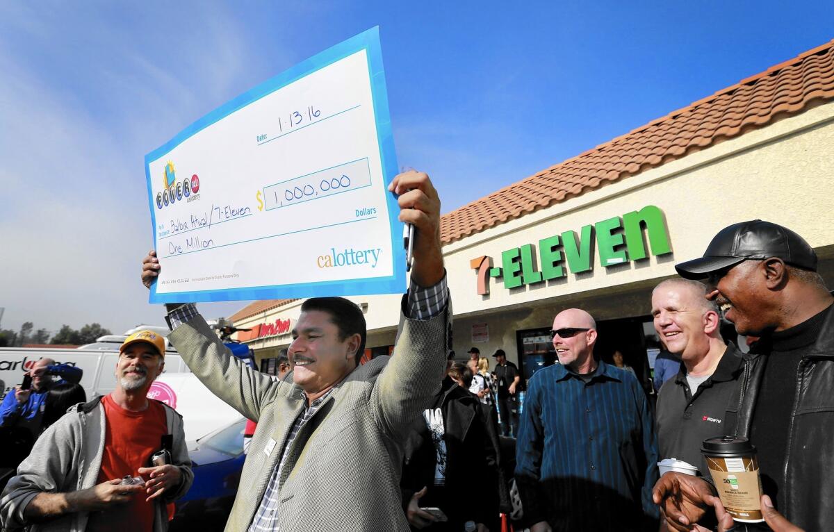 Balbir Atwal, owner of the 7-Eleven store in Chino Hills that sold a winning Powerball ticket, holds up an oversized prop check for $1 million, the business’ take for selling one of the three tickets that won the $1.5-billion jackpot.