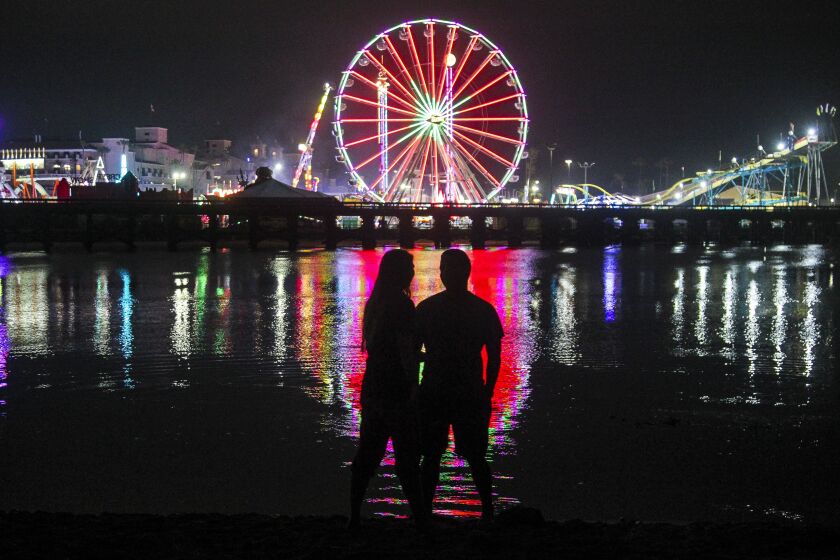 Samantha Sloss and Antonio Robles stand at the edge of the San Dieguito River as they watch the lights of the San Diego County Fair on Wednesday, June 12, 2019 in Del Mar, California.