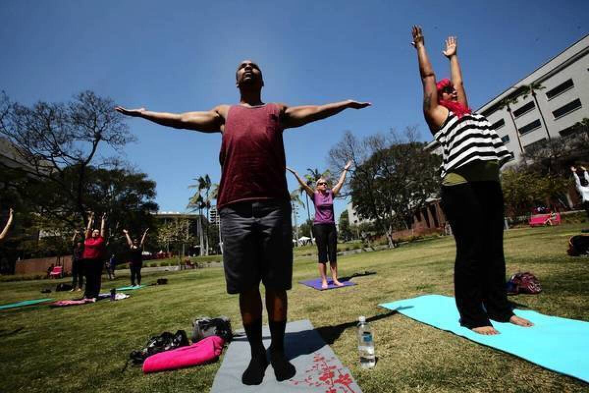 Jovon Washington, left, and Nay Jospine, both of Echo Park, participate in a free yoga class on the lawn at Grand Park.