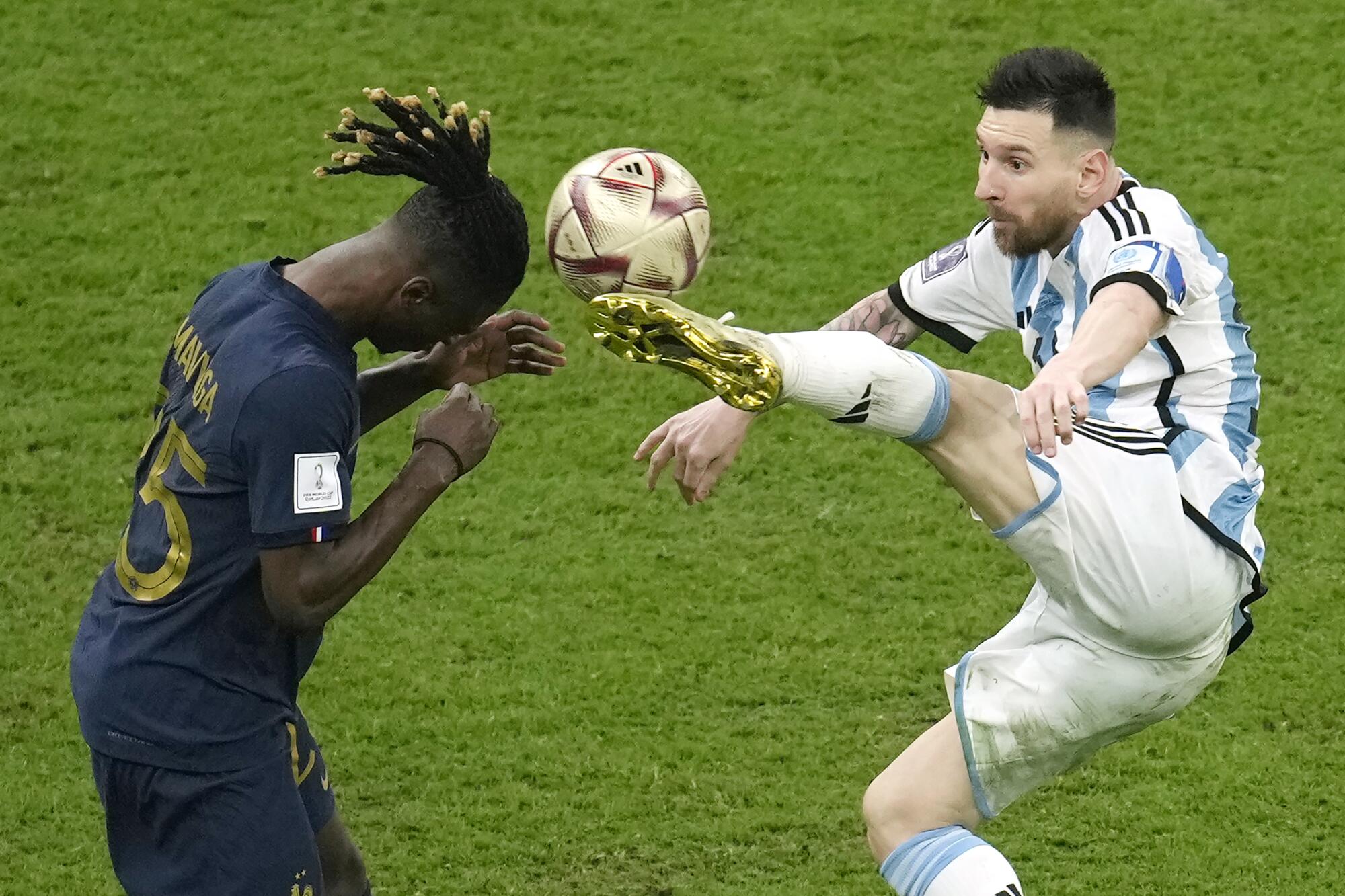 Argentina's Lionel Messi and France's Eduardo Camavinga aim for the ball while in mid-air.