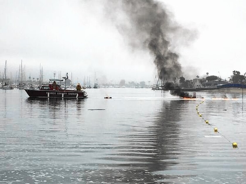Fire crews fight flames that broke out Friday morning on a fishing boat docked in Newport Harbor.