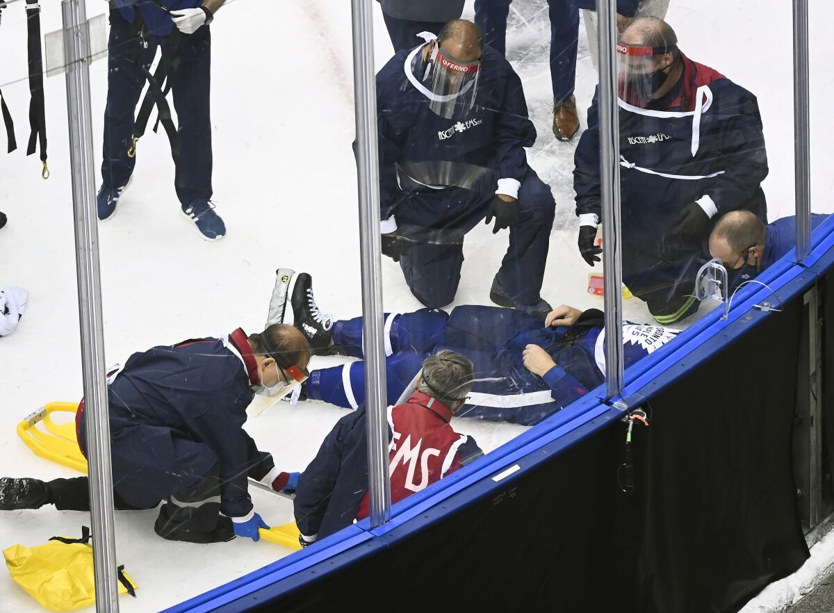 Medical staff surround Toronto Maple Leafs defenseman Jake Muzzin as he lays on the ice waiting to be placed on a stretcher as they play against the Columbus Blue Jackets during the third period of an NHL hockey playoff game Tuesday, Aug. 4, 2020 in Toronto. (Nathan Denette/The Canadian Press via AP)