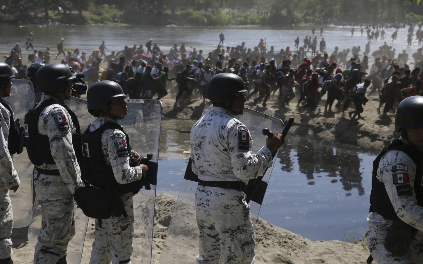 Mexican national guards stand on the bank of the Suchiate River where Central American migrants are crossing from Guatemala, near Ciudad Hidalgo, Mexico.