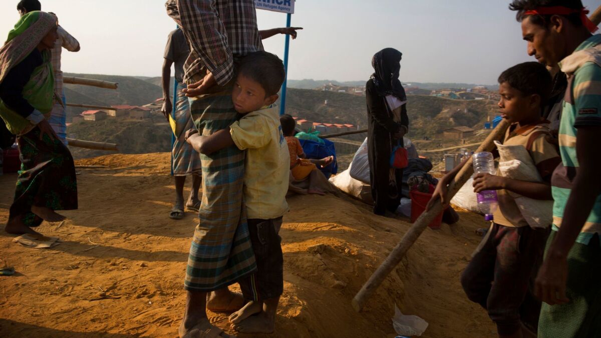 A Rohingya refugee boy clings to his father in the no-man's land between Myanmar and Bangladesh.