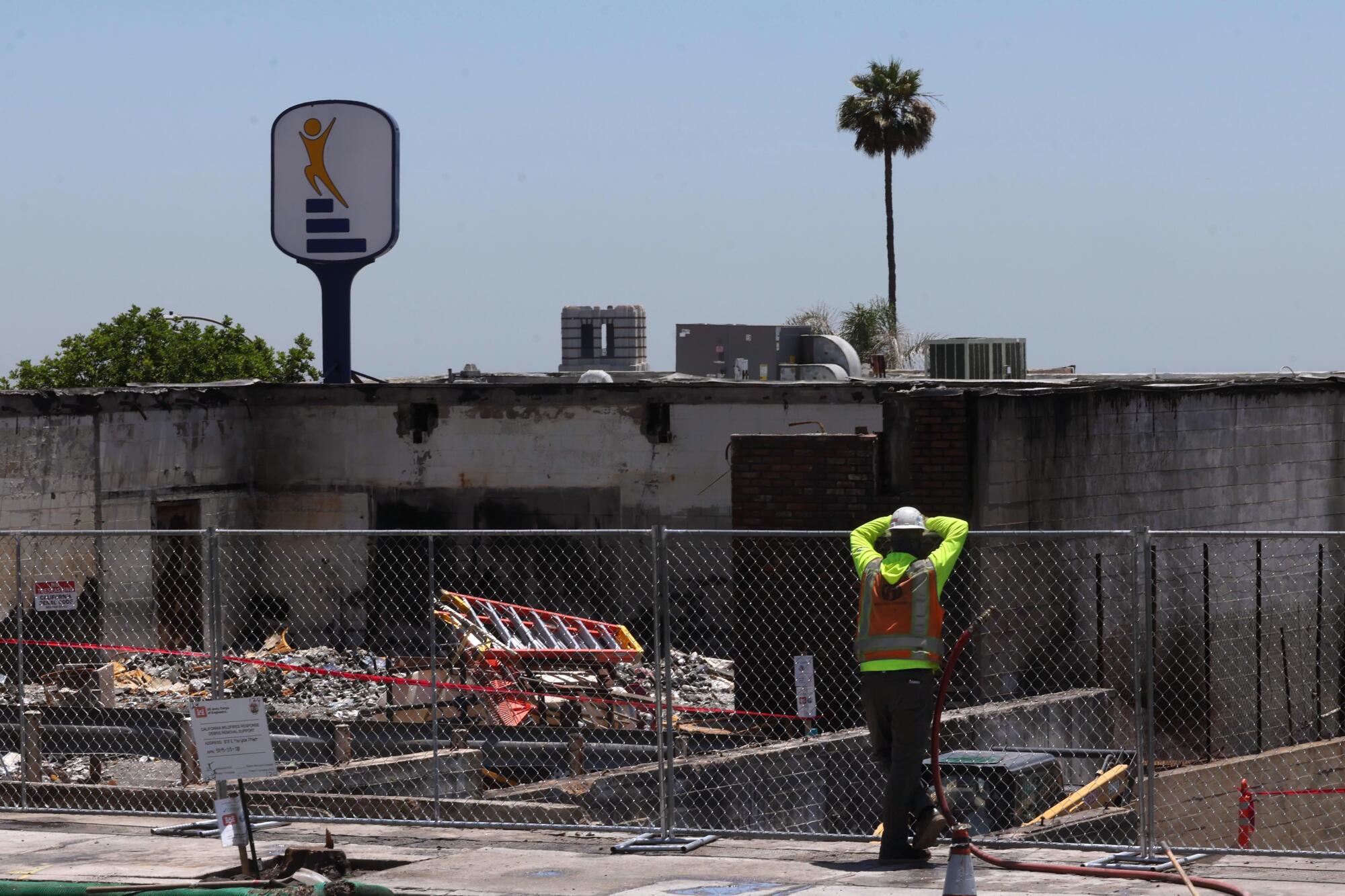 A worker looks over businesses, along Mariposa Street at Lake Avenue in Altadena, that were destroyed in the Eaton fire.