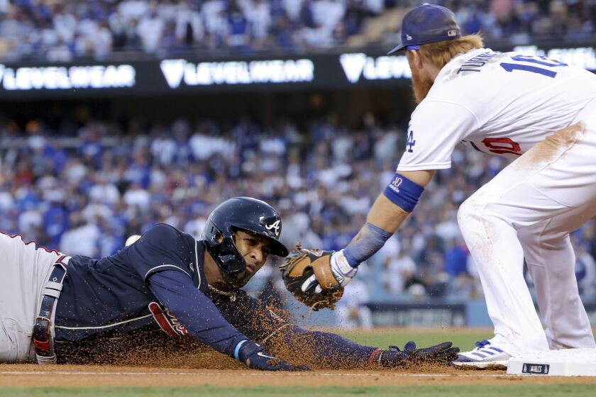 Los Angeles, CA - October 20: Atlanta Braves' Eddie Rosario, left, dives into third base after hitting a triple past the tag by Los Angeles Dodgers third baseman Justin Turner during the third inning in game four in the 2021 National League Championship Series at Dodger Stadium on Wednesday, Oct. 20, 2021 in Los Angeles, CA. (Robert Gauthier / Los Angeles Times)