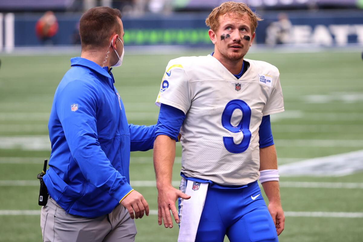 Rams quarterback John Wolford is escorted off the field after an injury.