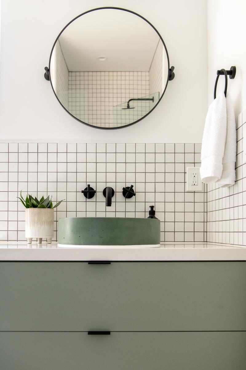 A bathroom with white tile and green cabinet