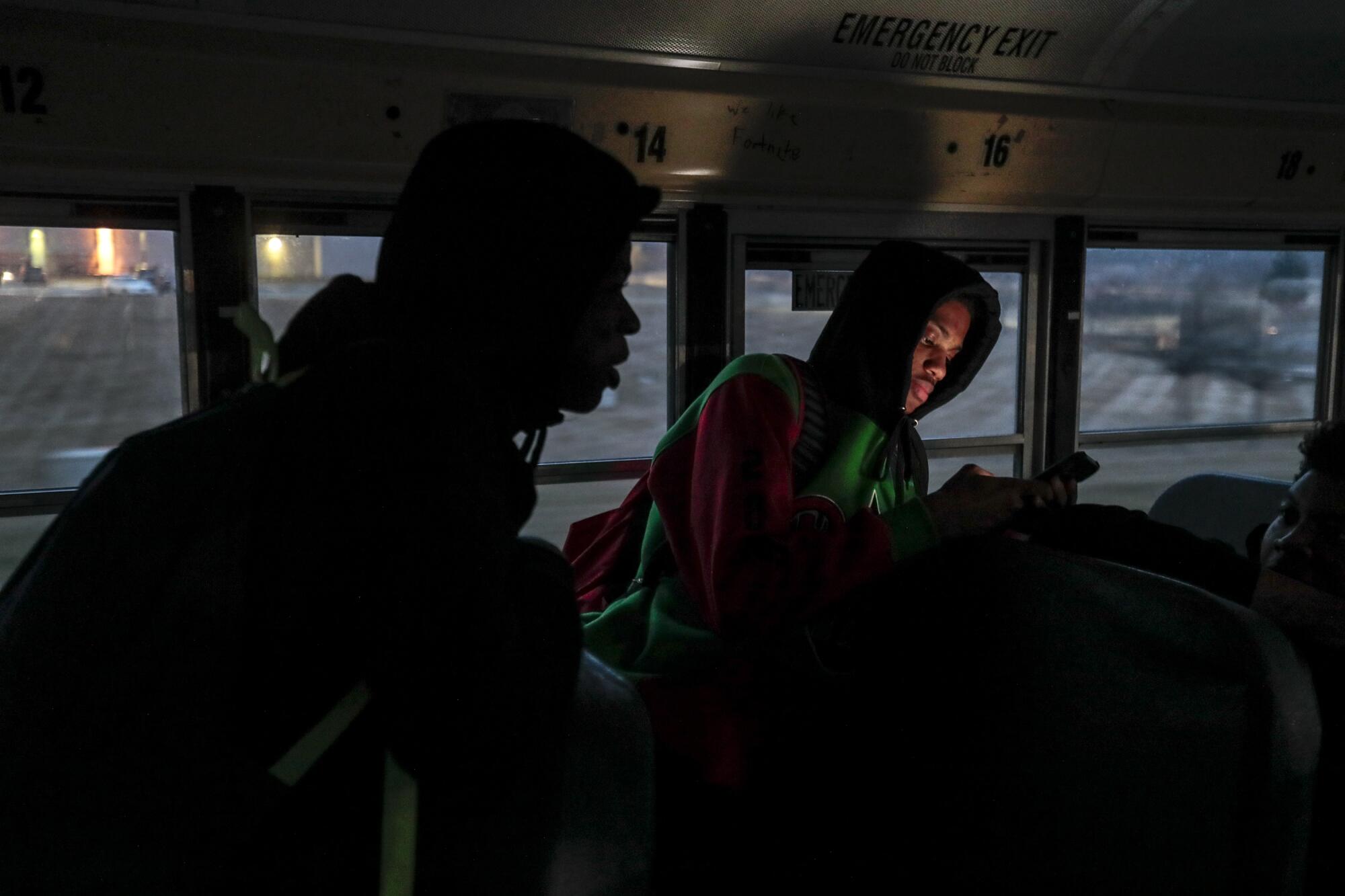 Dekobe Lemon checks his phone as the team rides the bus back to Flint after beating Davison.