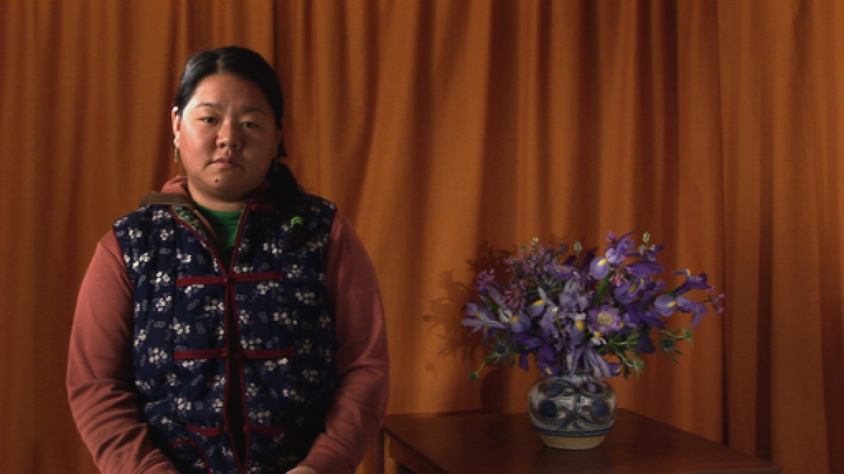 A video still shows a seated person beside flowers.