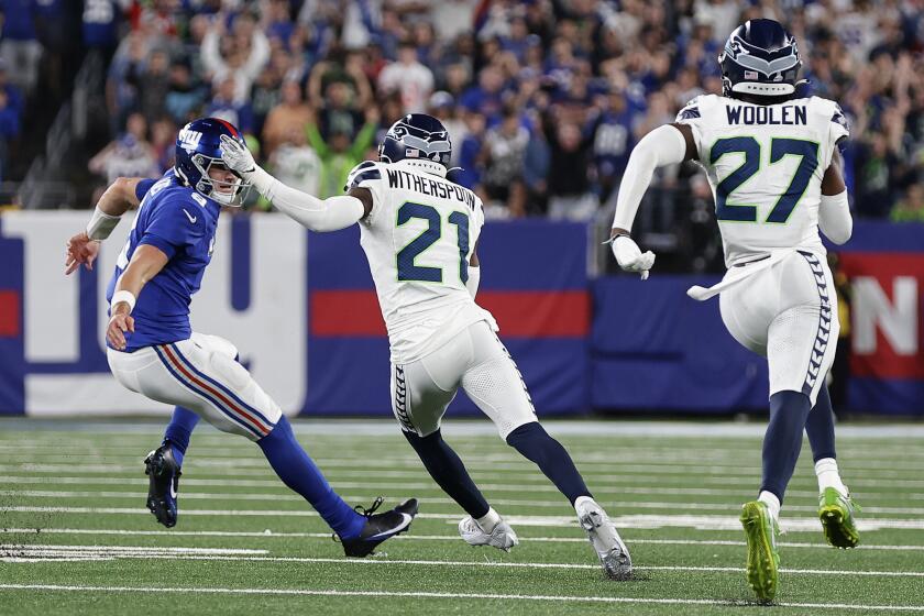 El cornerback de los Seahawks de Seattle Devon Witherspoon corre detrás del quarterback de los Giants de Nueva York Daniel Jones tras una intercepción para touchdown en el juego del lunes 2 de octubre del 2023. (AP Foto/Adam Hunger)