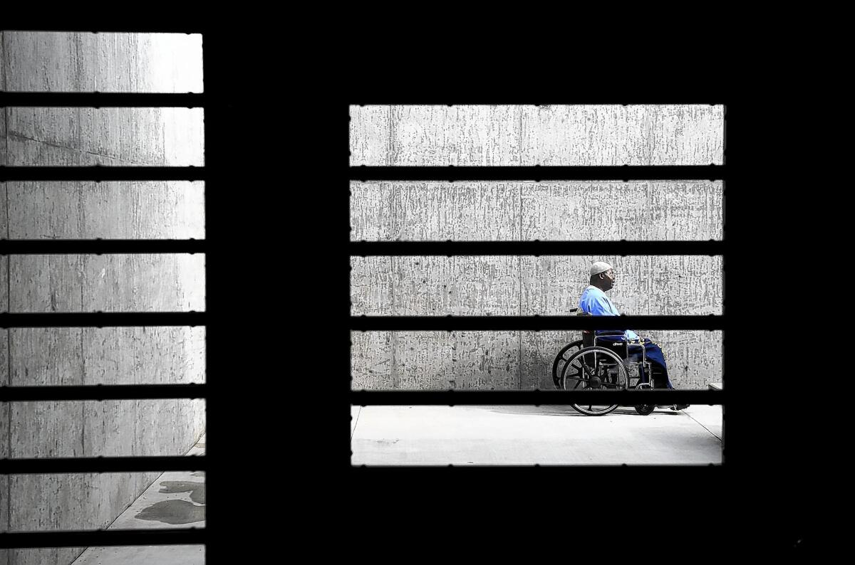An inmate sits in a courtyard at the California Health Care Facility outside Stockton. A federal judge Tuesday ordered California to stop the practice of temporarily housing disabled inmates in isolation units while awaiting suitable cell assignments.