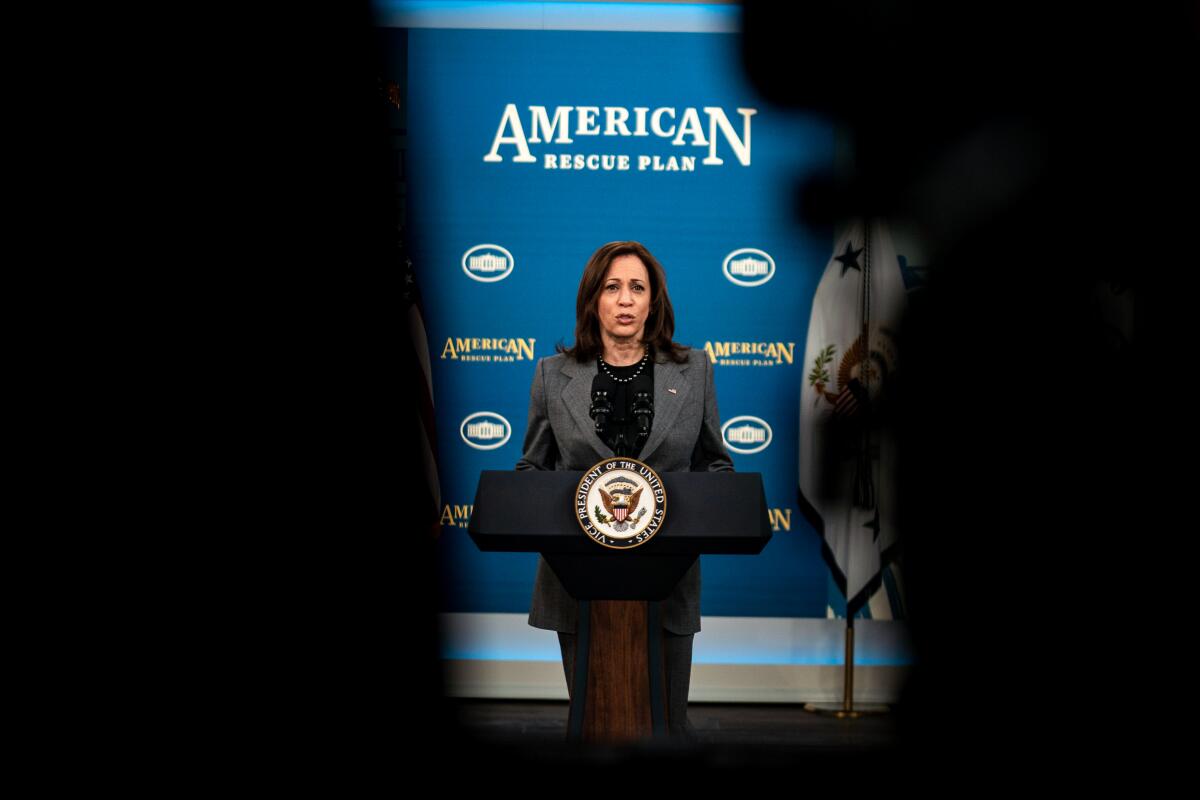 Kamala Harris speaks before a backdrop that says "American Rescue Plan"