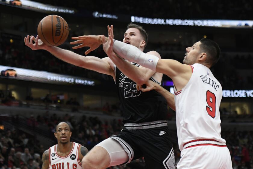 San Antonio Spurs' Jakob Poeltl (25) goes up to shoot while being fouled by Chicago Bulls' Nikola Vucevic (9) during the first half of an NBA basketball game Monday, Feb. 6, 2023, in Chicago. (AP Photo/Paul Beaty)