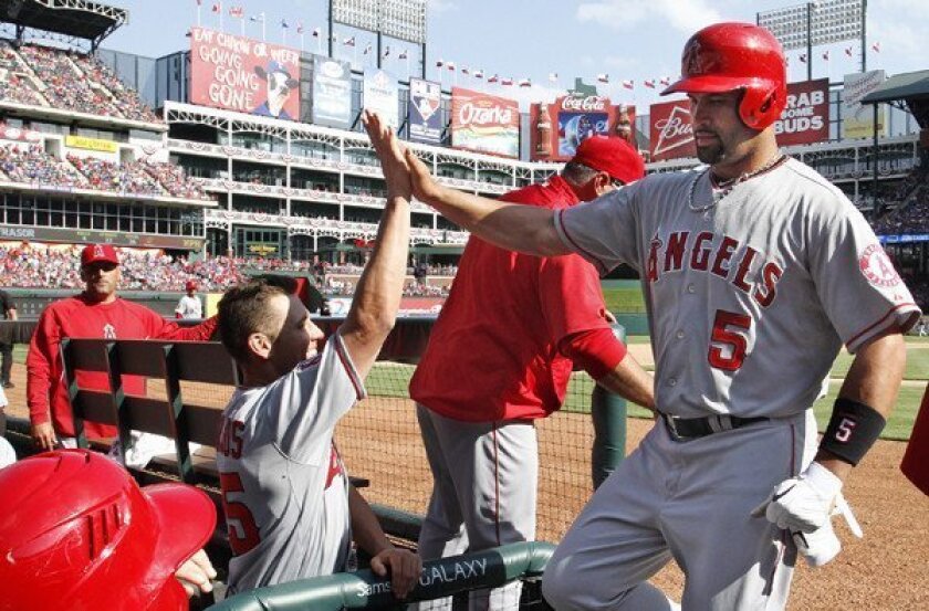 Angels first baseman Albert Pujols is greeted by Peter Bourjos as he returns to the dugout following a home run in the sixth inning Saturday afternoon in Texas.
