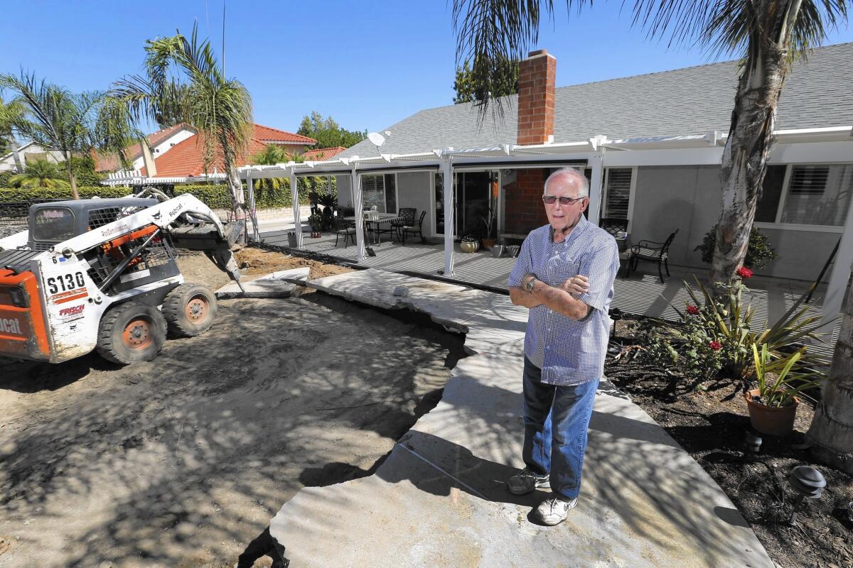 Yorba Linda homeowner David Harms watches as the former pool in his backyard is filled. He's replacing the pool with artificial grass and pavers.