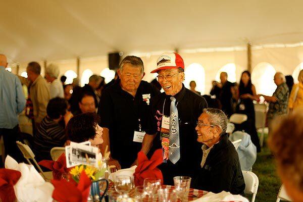 Bacon Sakatani, wearing a cap, and his friend Keiichi Ikeda, to his left, who were both interned at Heart Mountain in 1942, greet fellow internees George Fujimoto and his wife, Nobu, at an opening dinner.