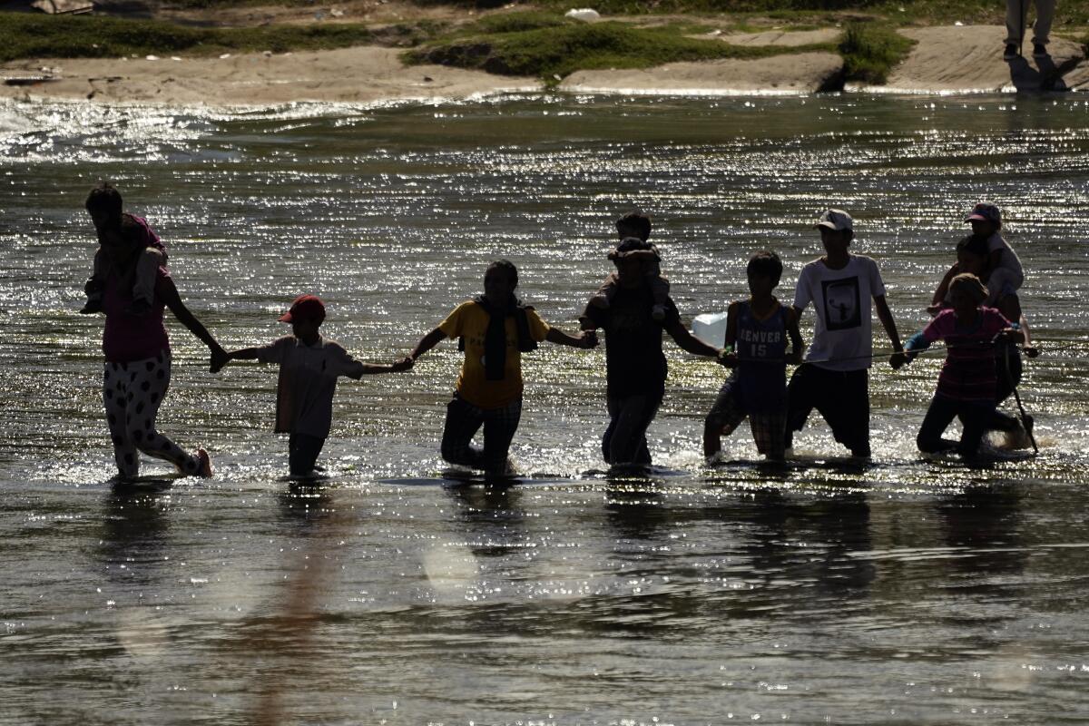 Migrantes forman una cadena humana para cruzar el Río Bravo.