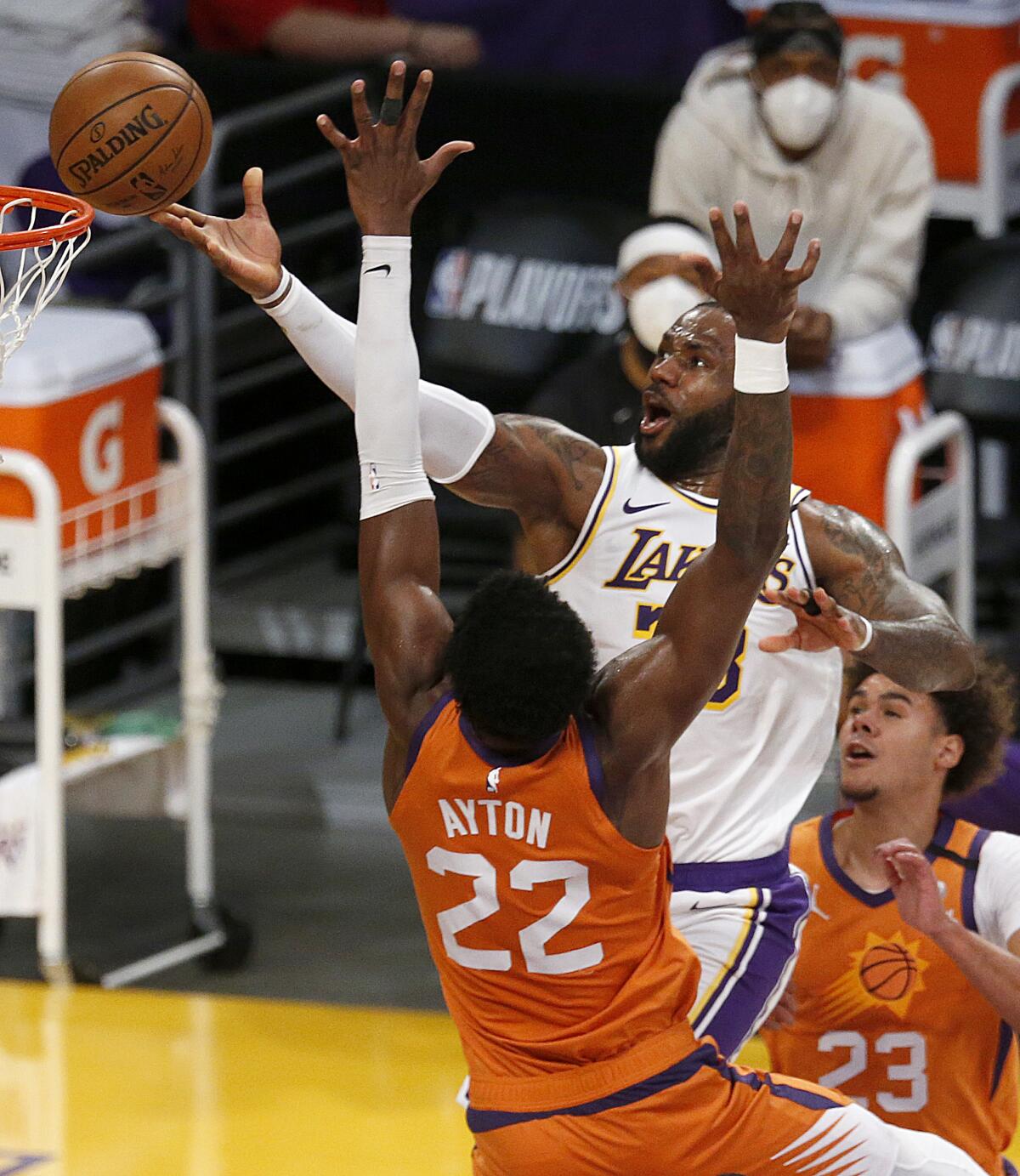 Lakers forward LeBron James scores on a layup over Suns center Deandre Ayton.