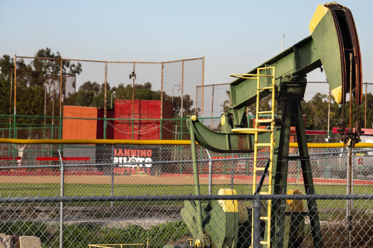 An oil rig in the foreground and a playing field behind.
