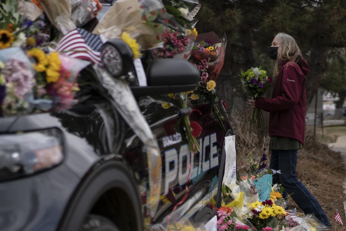 Flowers on a police car, with a mourner next to it