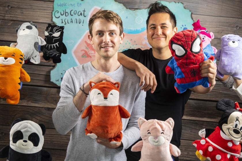 LOS ANGELES, CA --DECEMBER 12, 2018 --Zac Park, left and Spencer Markel, co-chief executives and founders of Cubcoats, a Los Angeles clothing company that makes children's hoodies that fold into stuffed animals, are photographed holding one of their creations, Park with their own design and Markel with a licensed one, and surrounded by many of their others, at their Los Angeles, CA, office, Dec 12, 2018. (Jay L. Clendenin / Los Angeles Times)