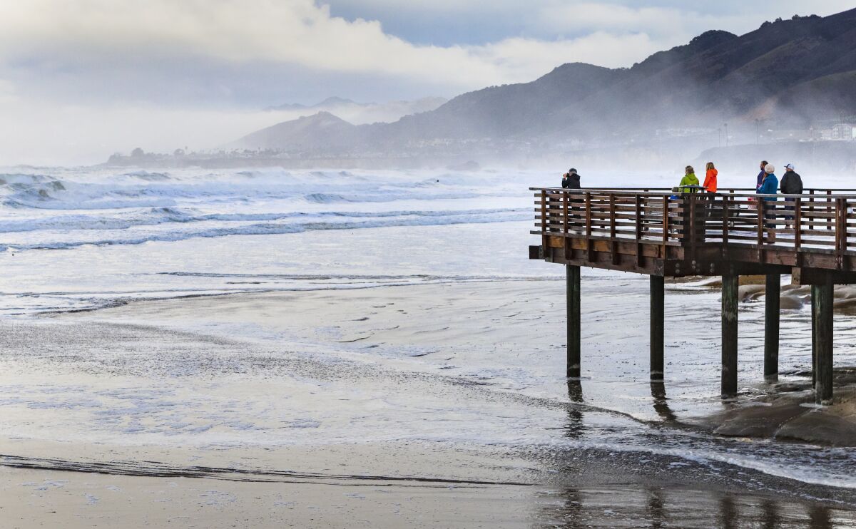 FILE - A group of people gather to watch the storm surge from high tides and big surf in the morning in Pismo Beach, Calif., Thursday, Jan. 7, 2016. A federal agency is taking a step toward designating a new national marine sanctuary off the central California coast that would be named for the indigenous people of the region. The National Oceanic and Atmospheric Administration announced Tuesday, Nov. 9, 2021, that it is seeking public comment on the proposed Chumash Heritage National Marine Sanctuary. (Joe Johnston/The Tribune of San Luis Obispo via AP, file)