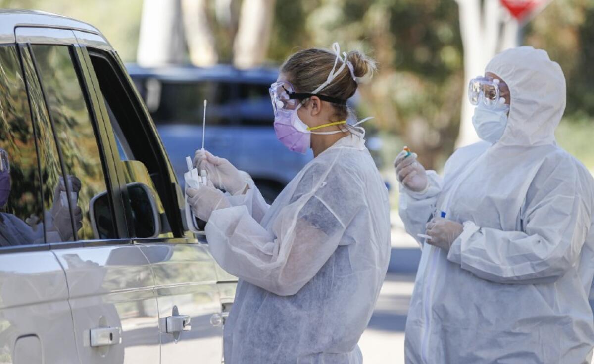 At a drive up testing site, Covid Clinic medical assistants Rhiannon Weik (left) and Arely Gutierrez (right) collect samples for Coronavirus COVID-19 testing at the San Elijo campus of Mira Costa College in Cardiff on Wednesday, Apr. 15.
