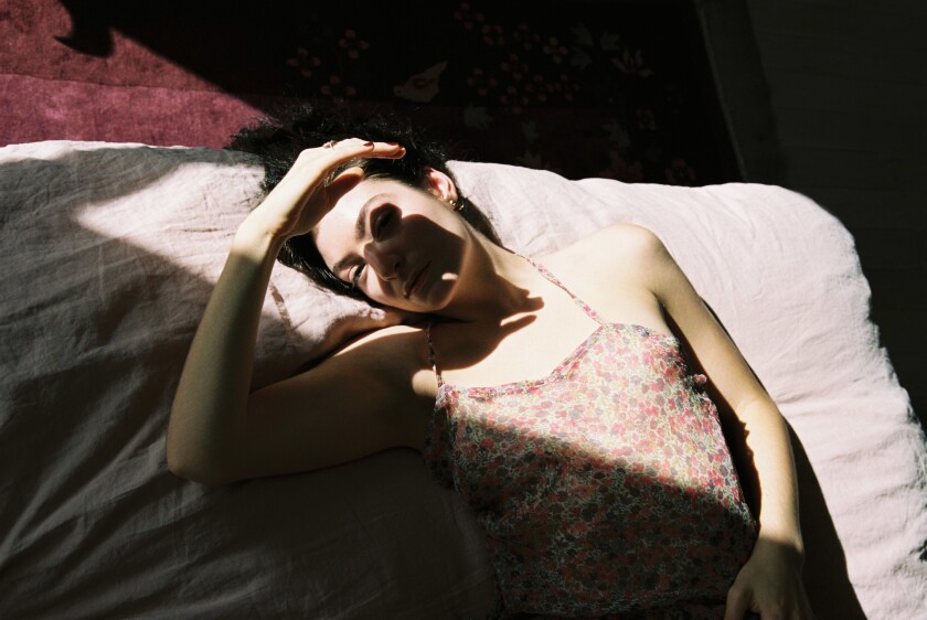 A woman lying down and squinting at the bright light