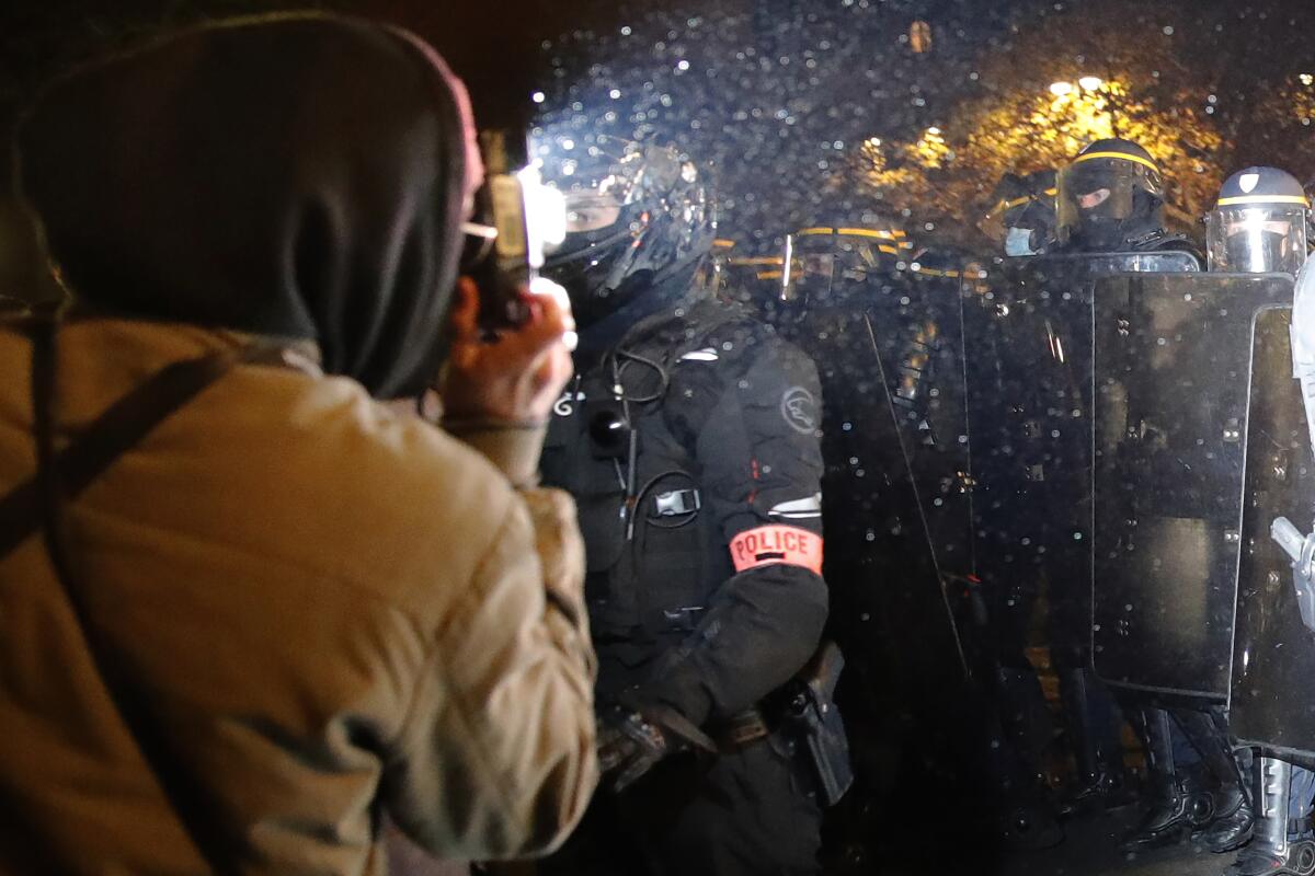 A demonstrator takes a picture of police officers in Paris during a Nov. 21 protest.