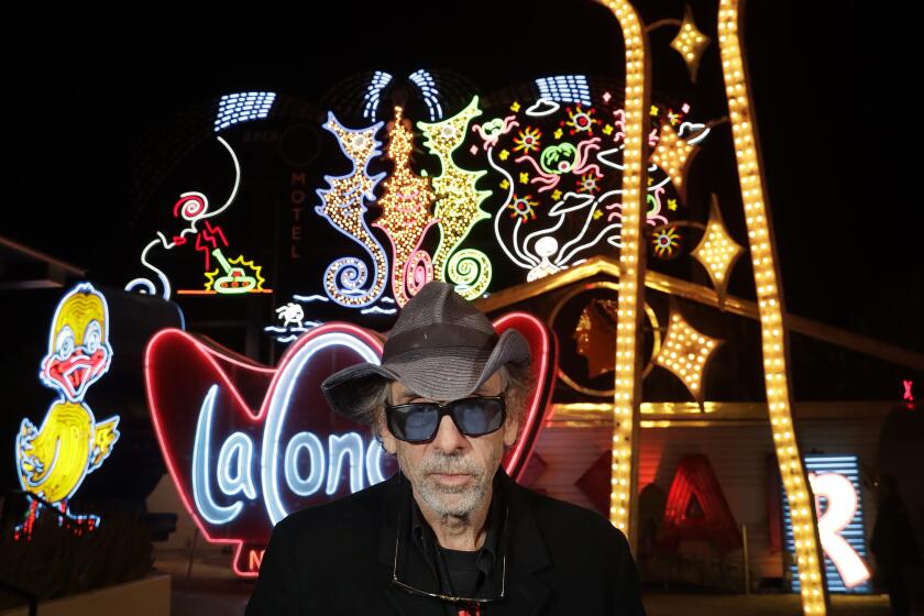 Tim Burton in front of "Neon Grid Wall" and "Lost Vegas Sign Tower" at his "Lost Vegas" exhibit at the Neon Museum in Las Vegas.